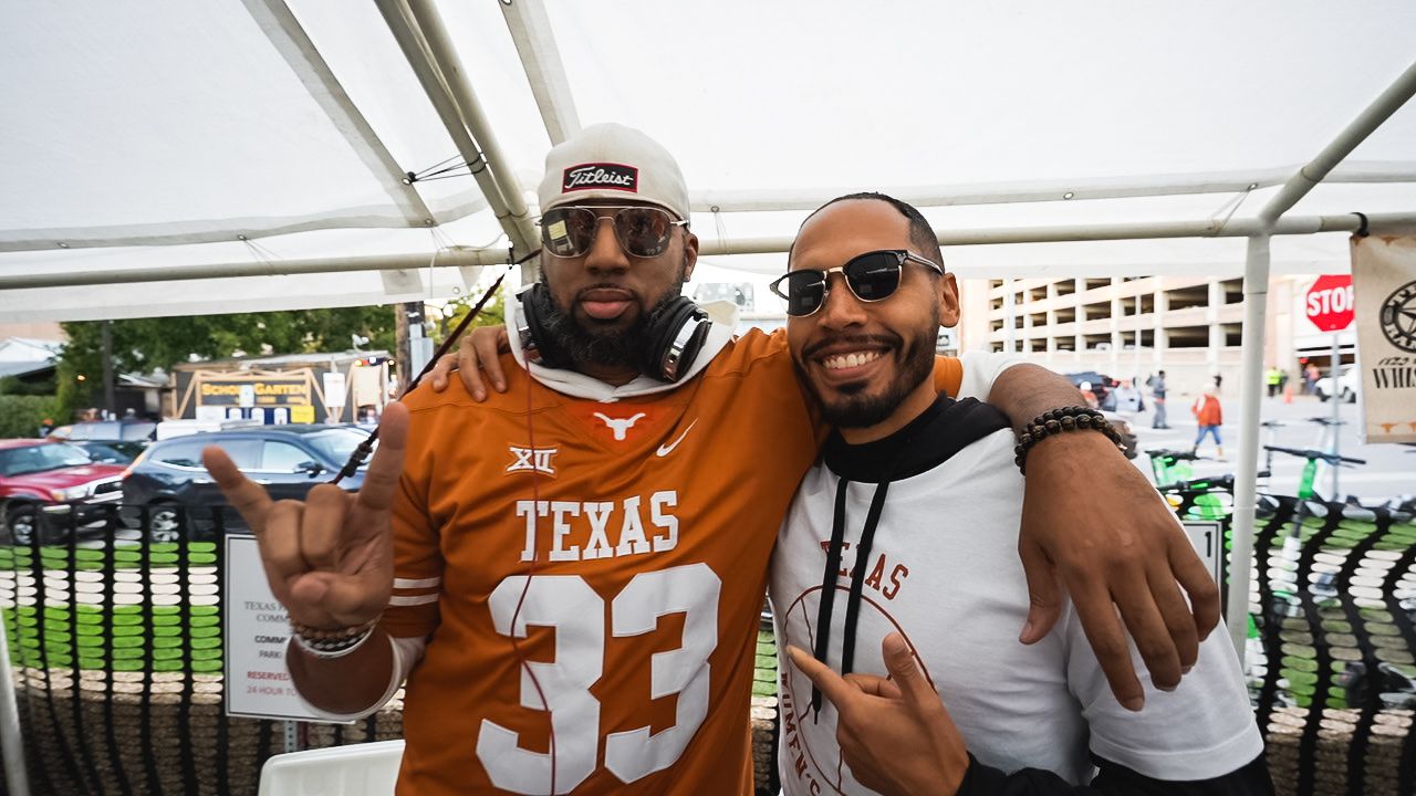 Two sports fans in Texas Longhorns gear posing together at a tailgate party.