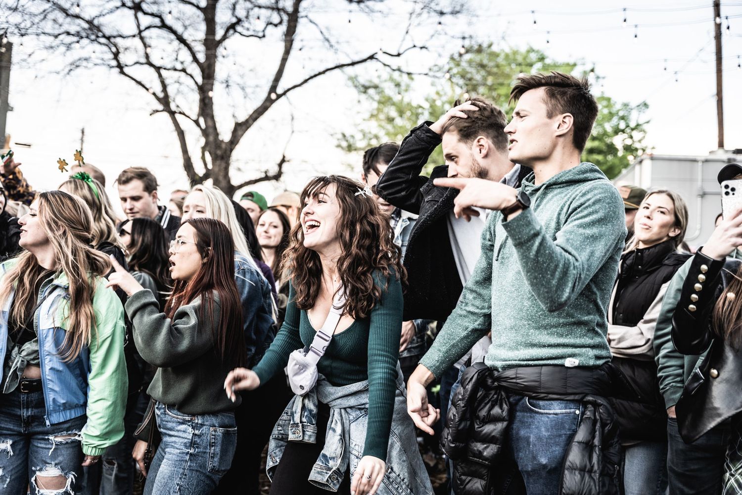 Enthusiastic crowd singing along at outdoor music performance.