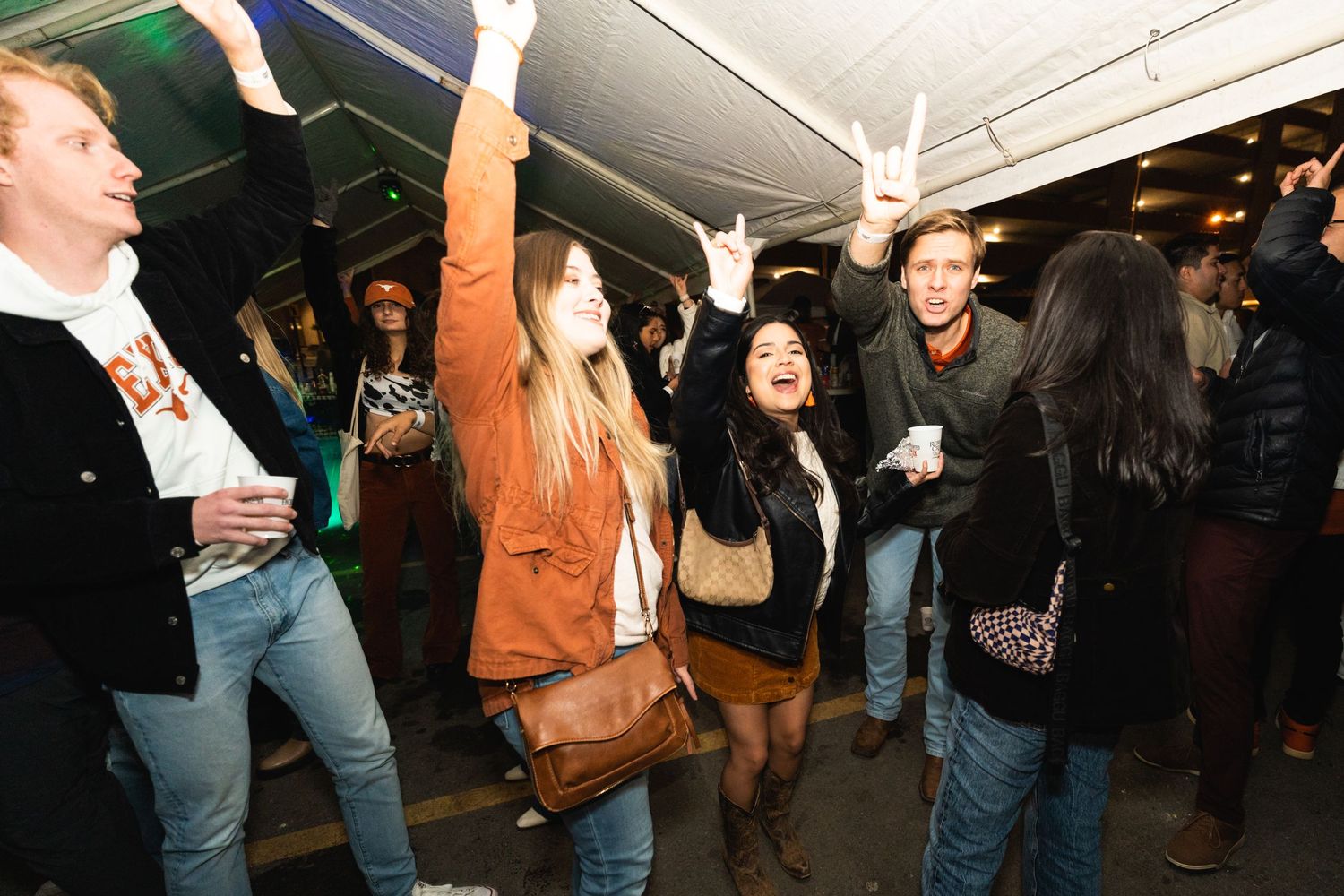 People dancing and having fun at an indoor party with green lighting effects.