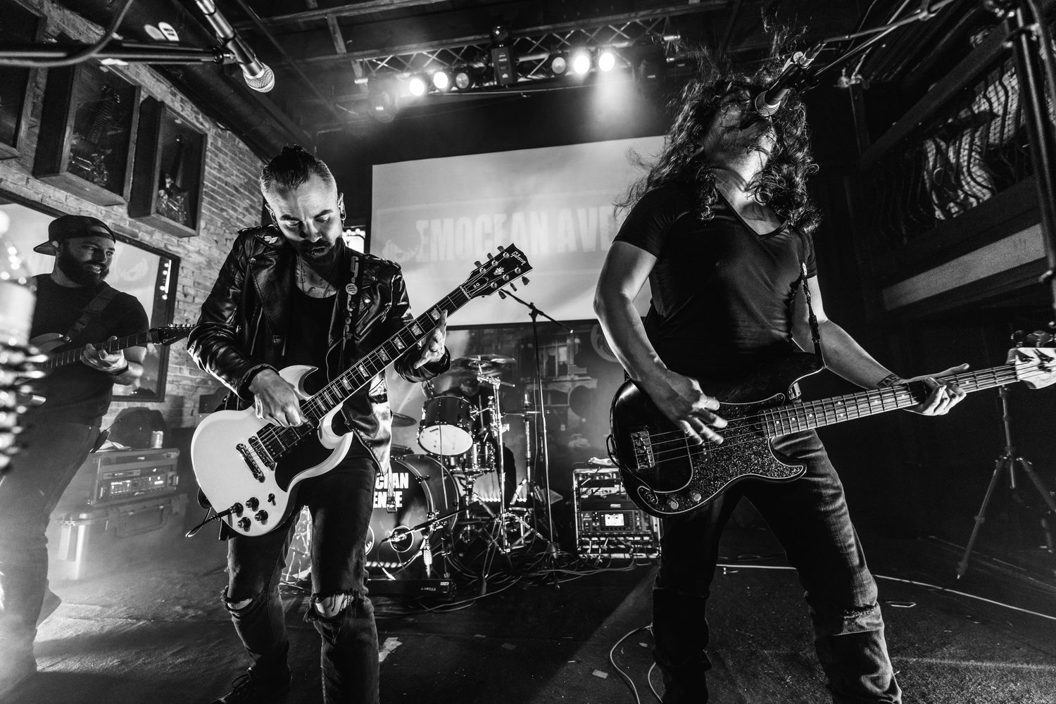 Black and white shot of band members performing with guitars on dimly lit stage.