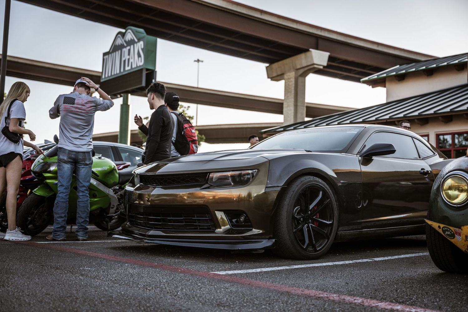 Low-angle shot of a modified black sports car with custom wheels at a car meet.