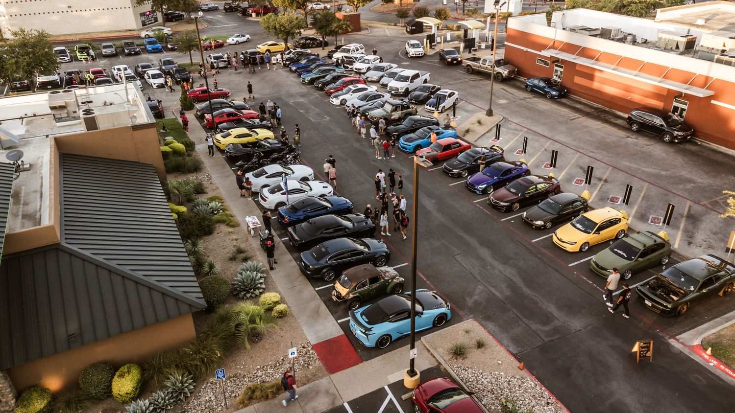 Overhead view of parked cars lined up at an outdoor automotive event.