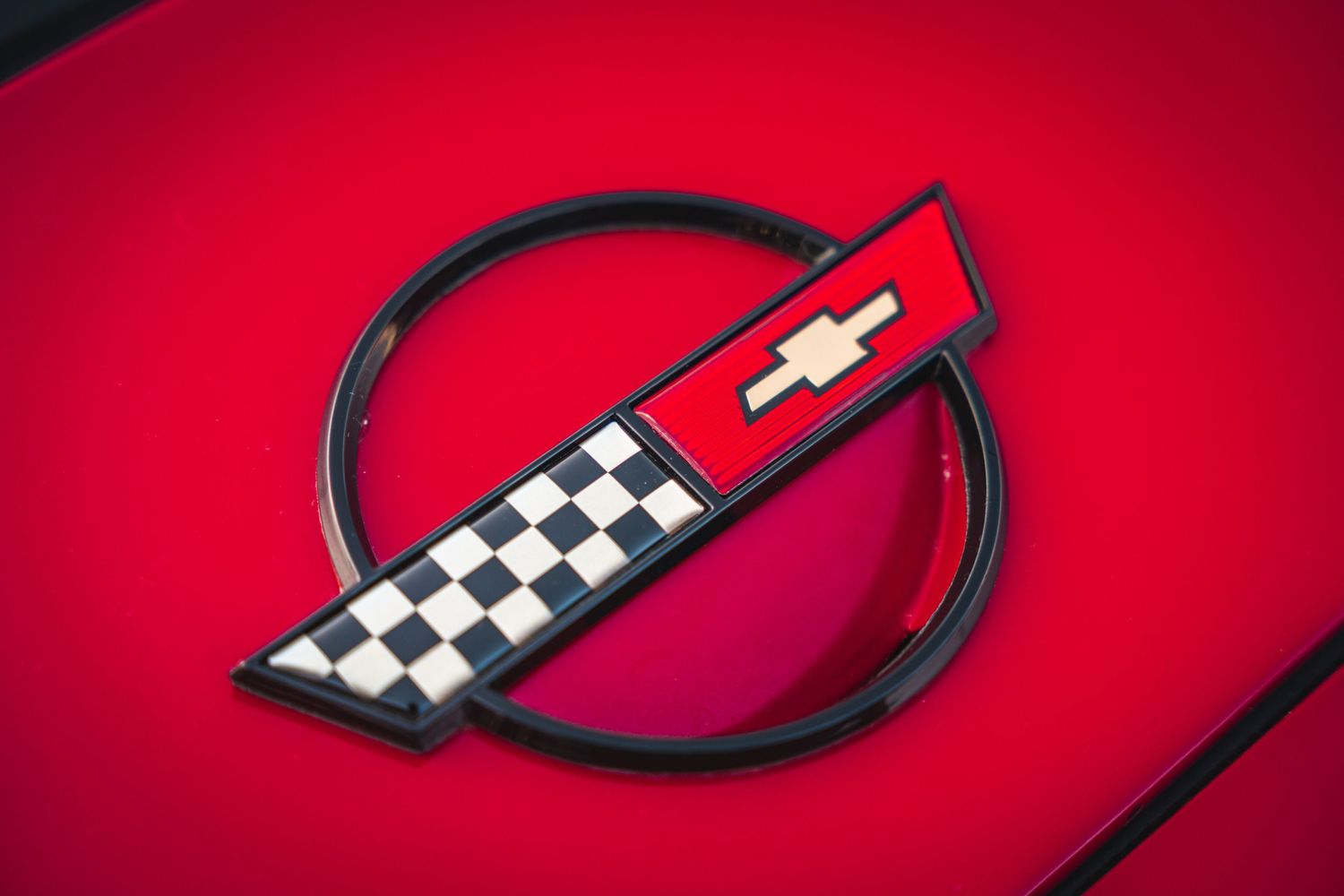Vintage Chevrolet Corvette emblem on red paint surface.