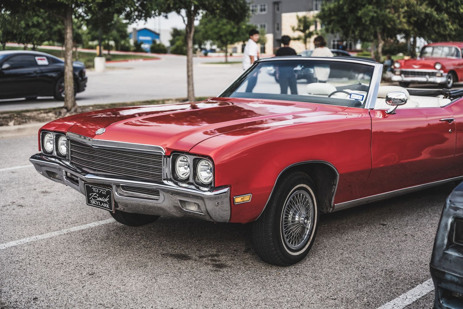 Classic red Buick Skylark convertible parked in a lot showing its distinctive front end design.