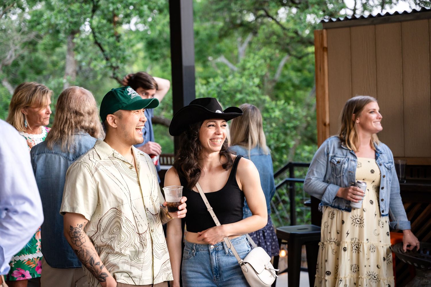 Guests mingle and socialize at an outdoor party on a covered patio.