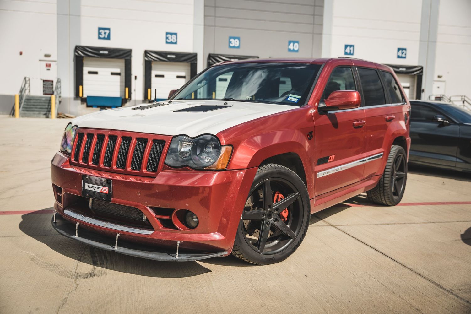 Red Jeep Grand Cherokee SRT8 performance SUV with black wheels parked at loading dock.