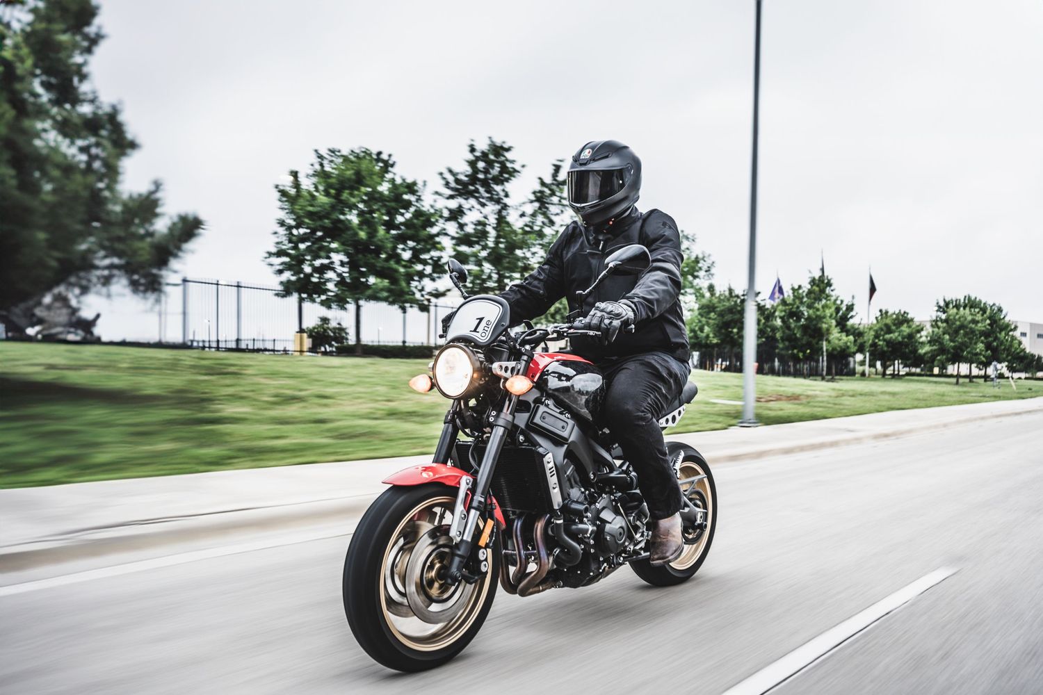 Rider in black protective gear navigating motorcycle through city streets.