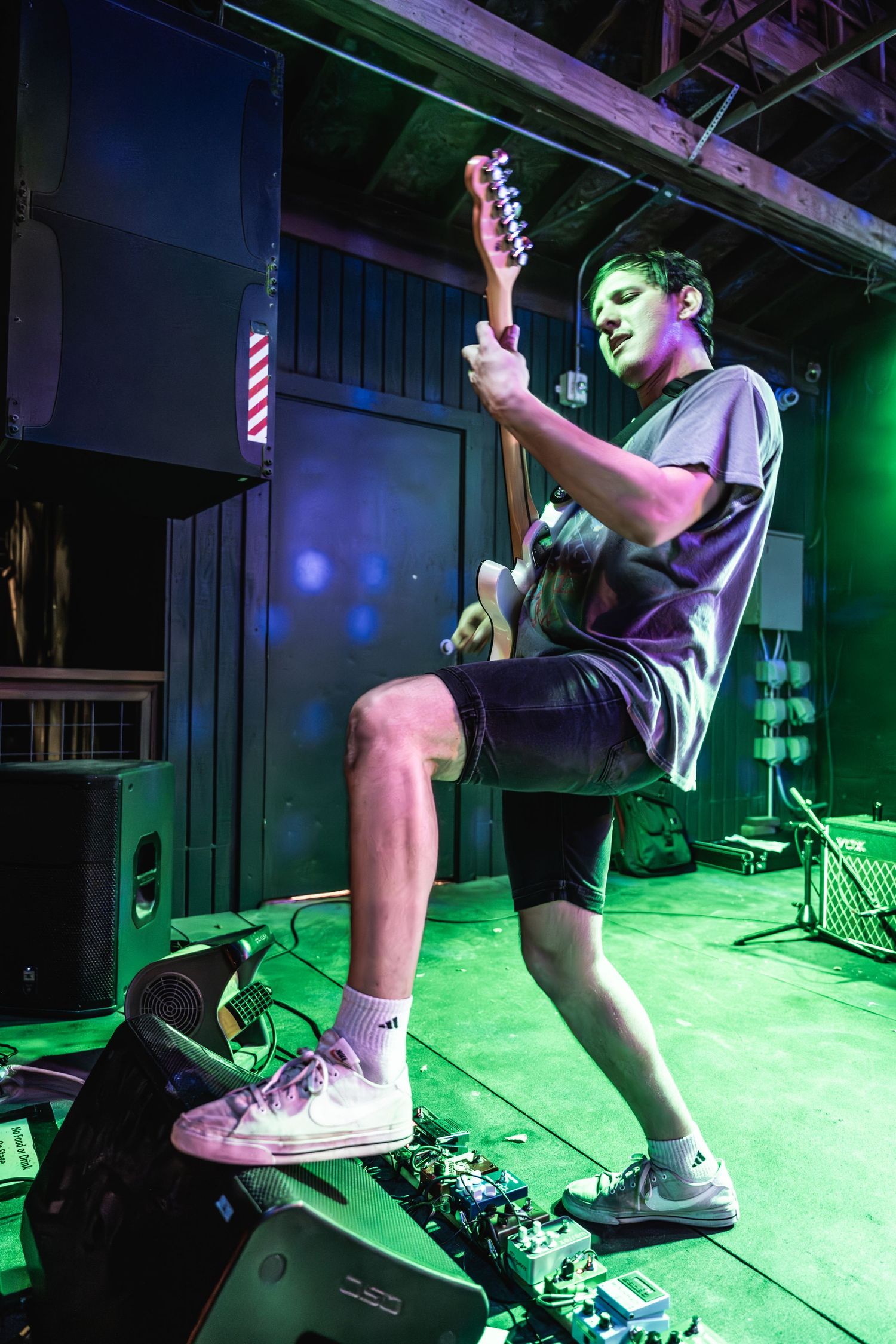 Guitarist performing on stage bathed in green stage lighting.