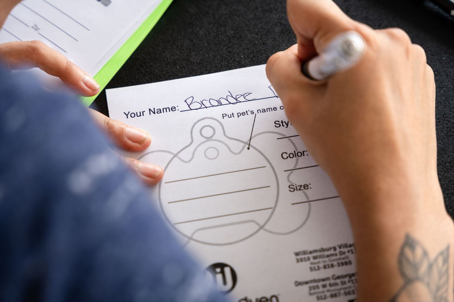 Close-up of hands filling out a form with a silver pen.