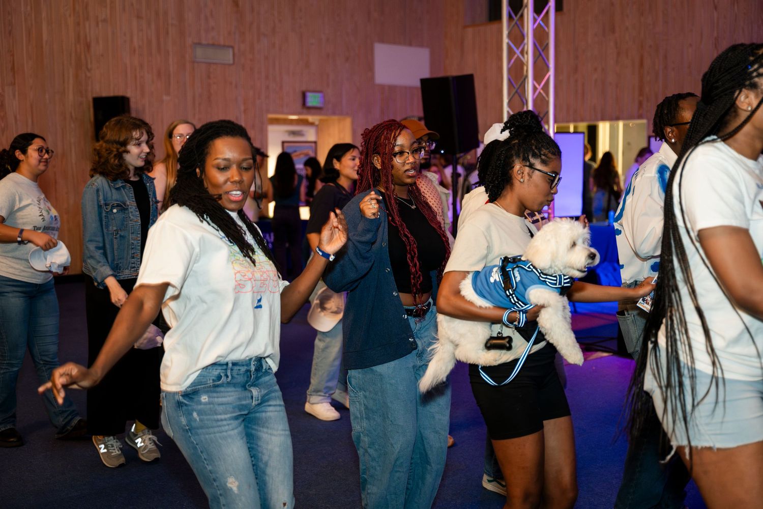 People dancing and enjoying themselves at a party with stage lighting and speakers in the background.