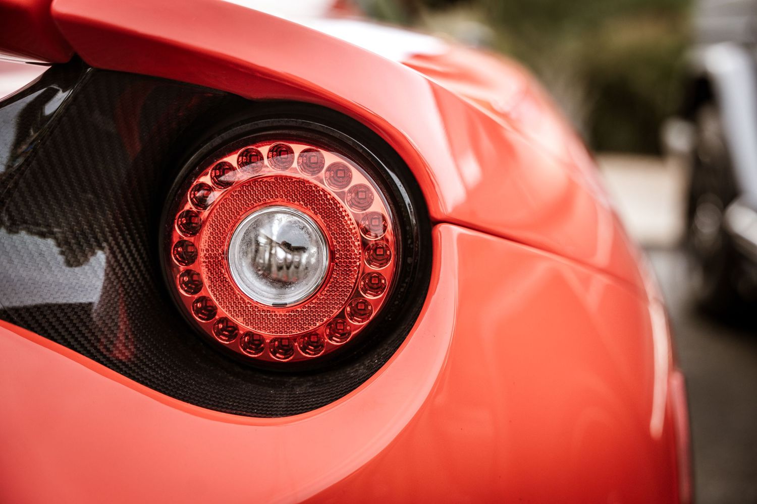 Close up detail shot of red circular LED tail light on luxury sports car.