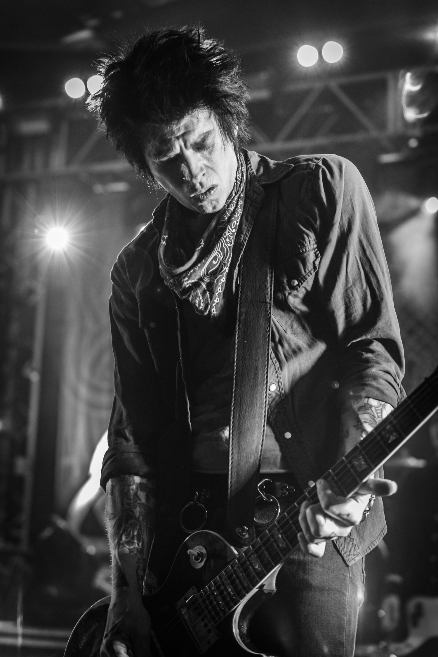 Black and white portrait of guitarist playing with intense expression during performance.