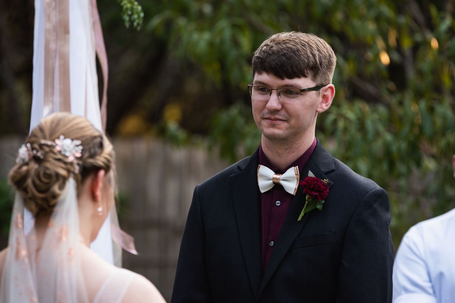 An emotional moment captured during an outdoor wedding ceremony with autumn foliage in background.