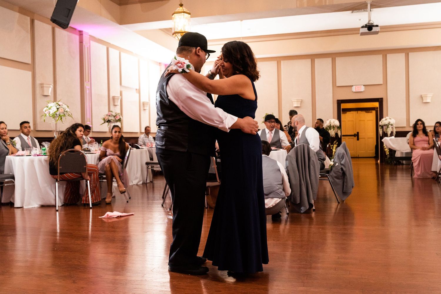 Dancers embrace on the dance floor during an elegant reception in a warm-lit ballroom.