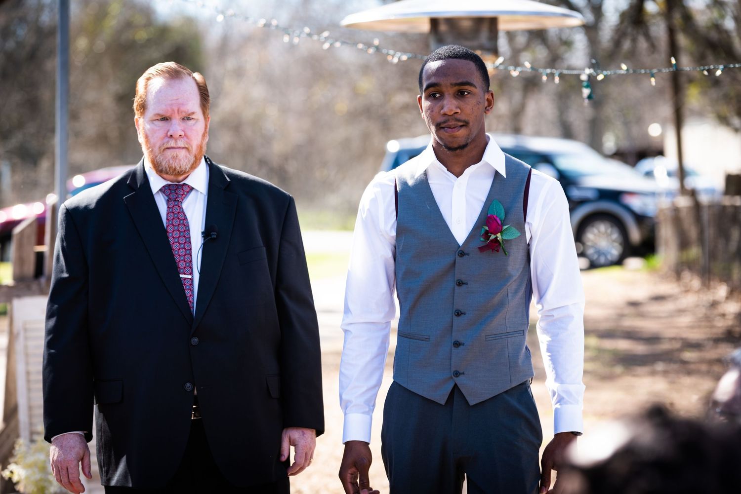 Two men in formal wedding attire walking together outdoors.