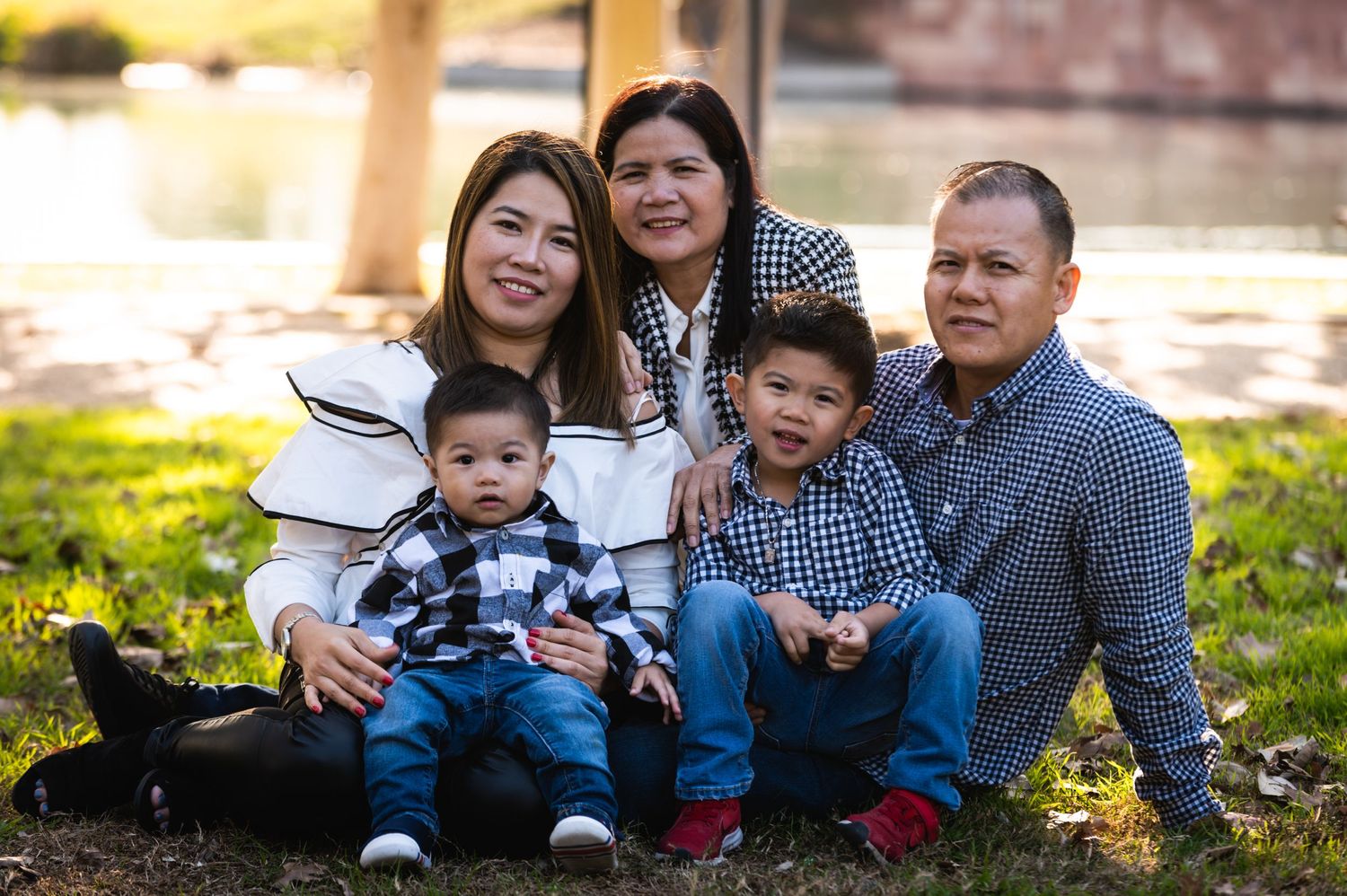 A family seated together outdoors on grass during golden hour in matching casual outfits.