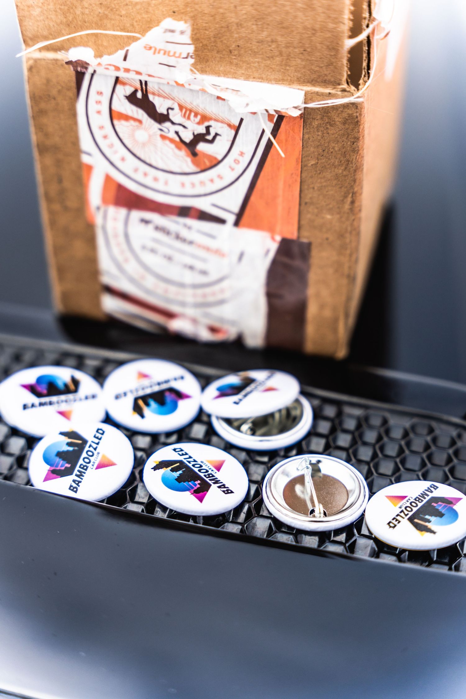Collection of automotive-themed buttons and badges displayed on a keyboard with a cardboard box.