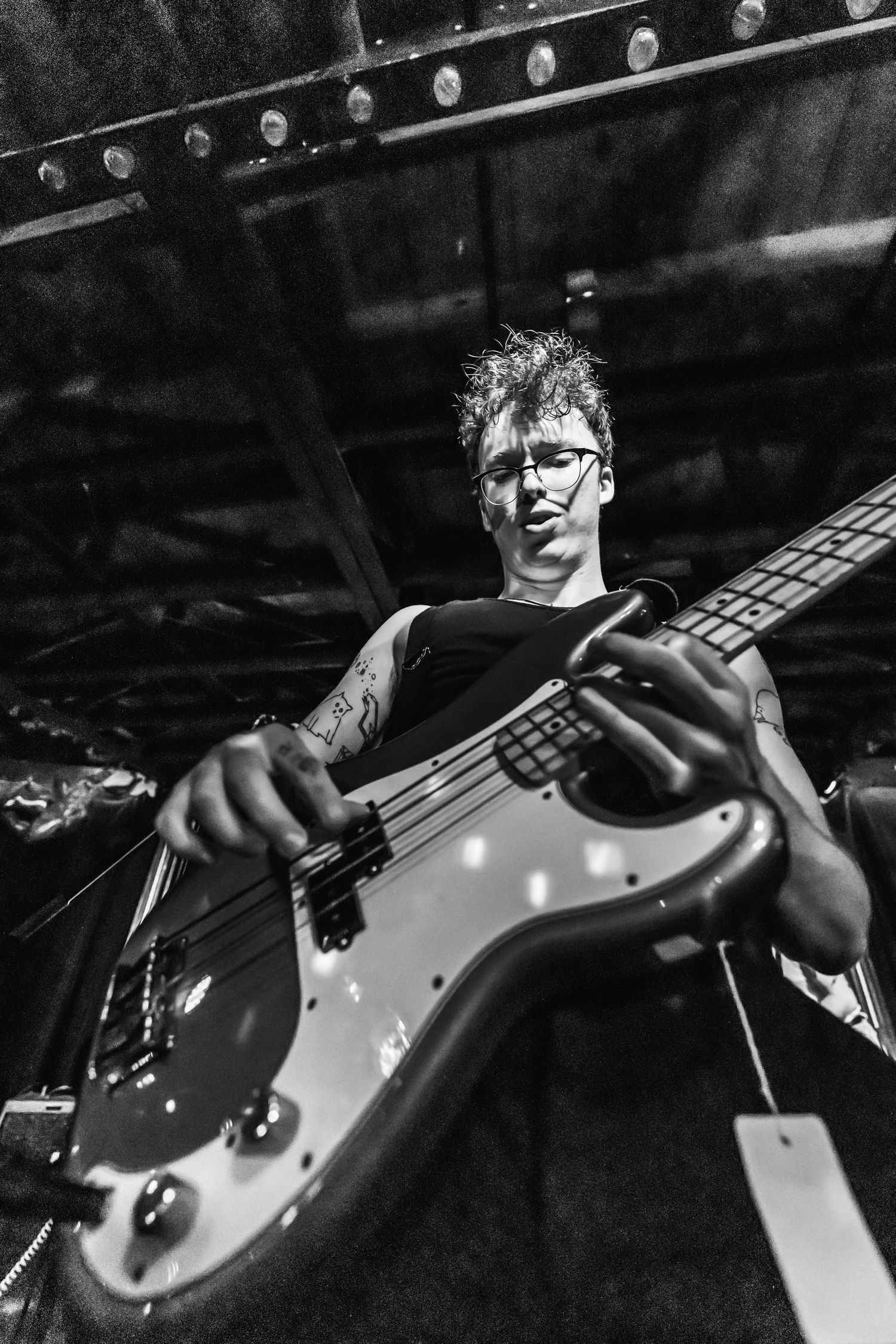 Black and white photo of a bassist performing on stage with dramatic lighting.