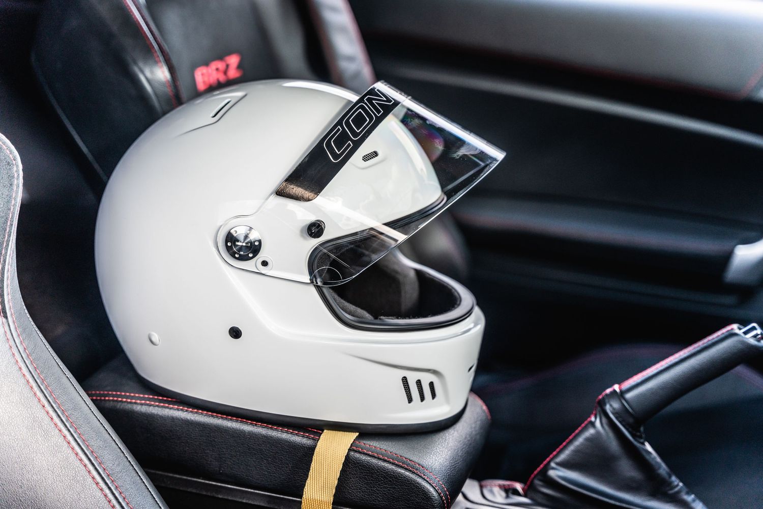 White racing helmet sitting on car seat interior.