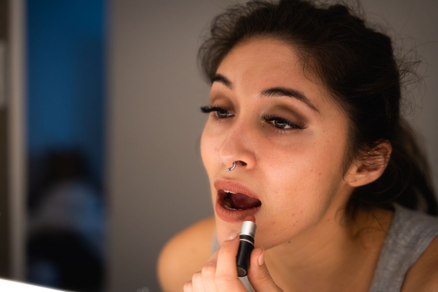 Close-up shot of someone applying dark lipstick in natural lighting.