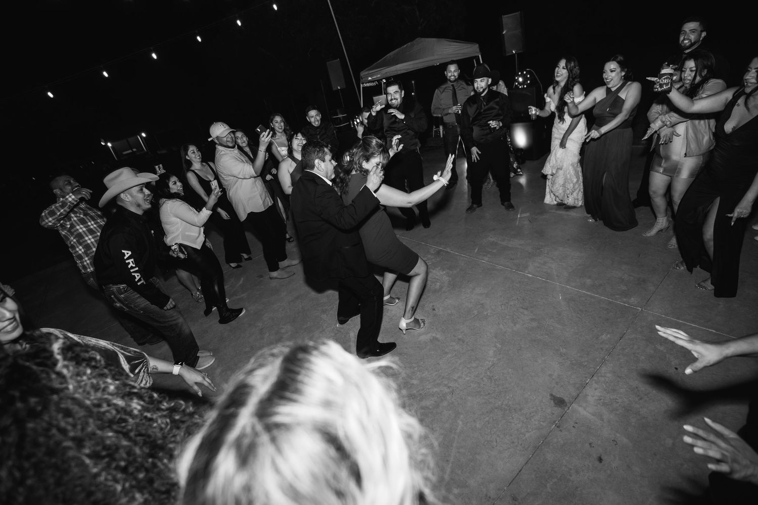 A black and white photo captures lively dancing at a wedding reception.