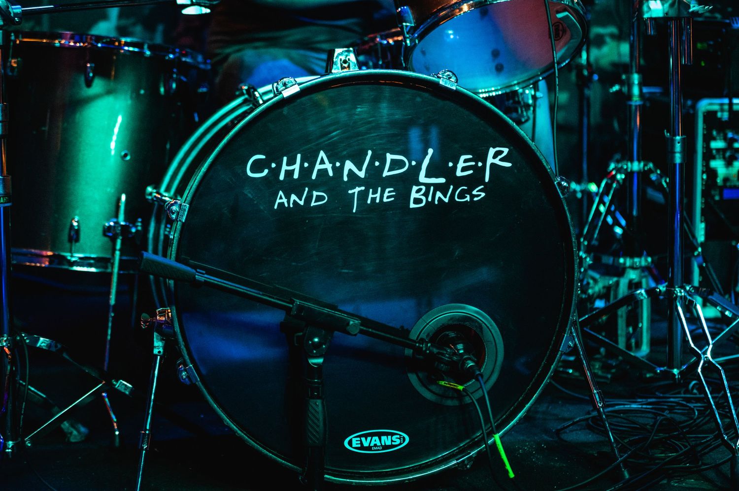 Black bass drum with 'Chandler and the Band' text visible under turquoise stage lighting.
