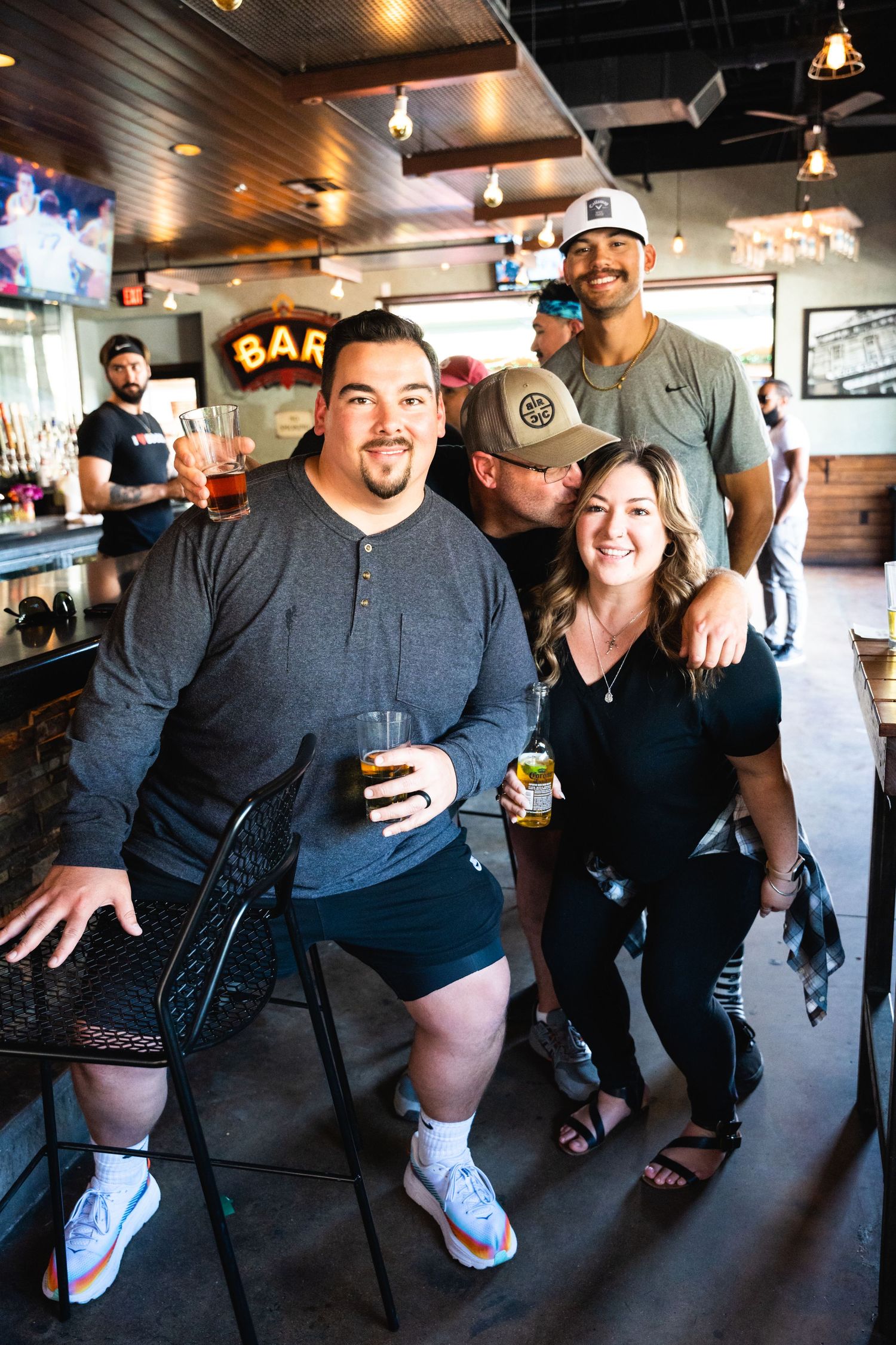 Group gathering at a bar with casual drinks and smiles in relaxed indoor setting.