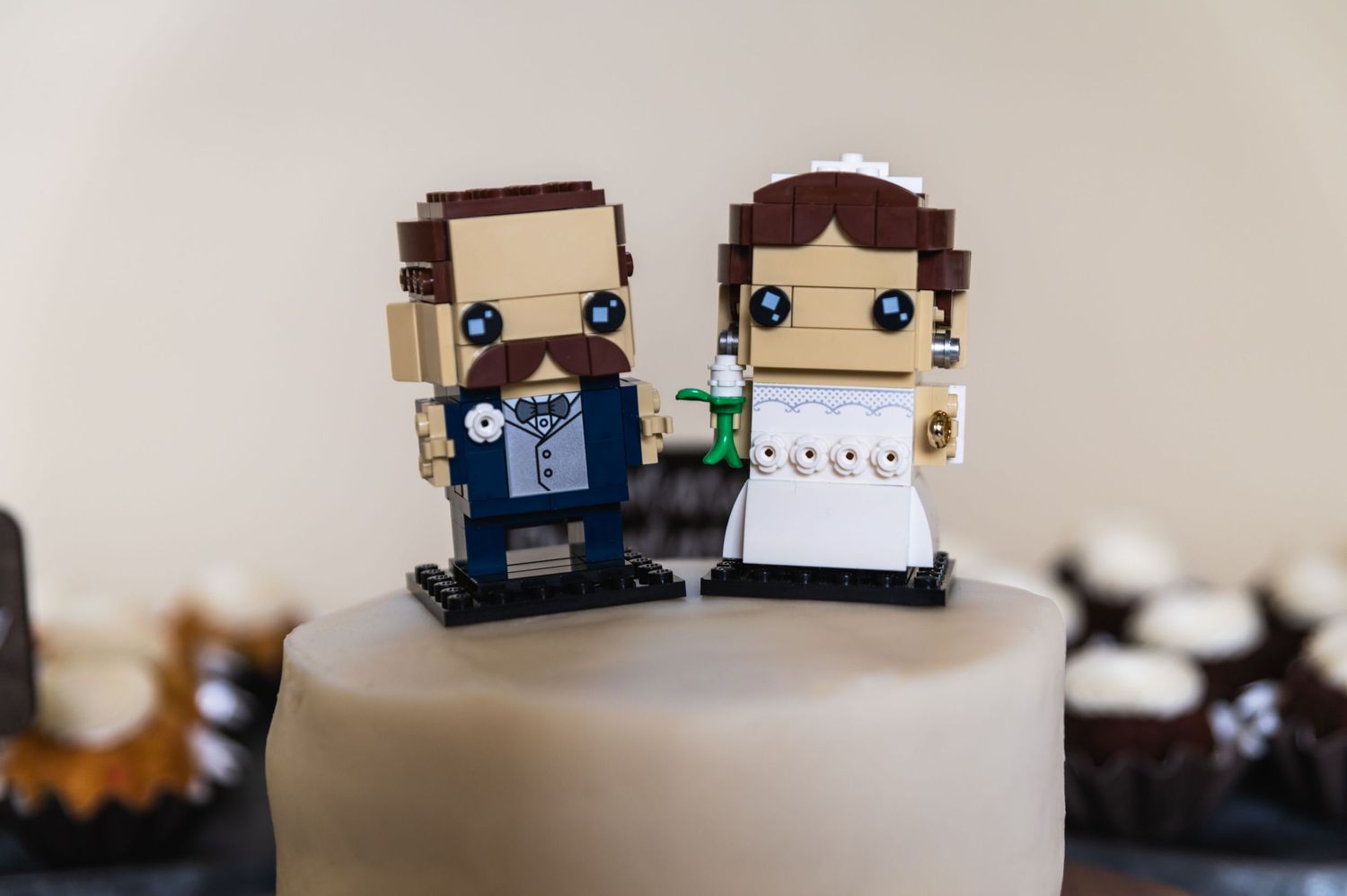 Custom LEGO bride and groom cake toppers standing on white frosting.