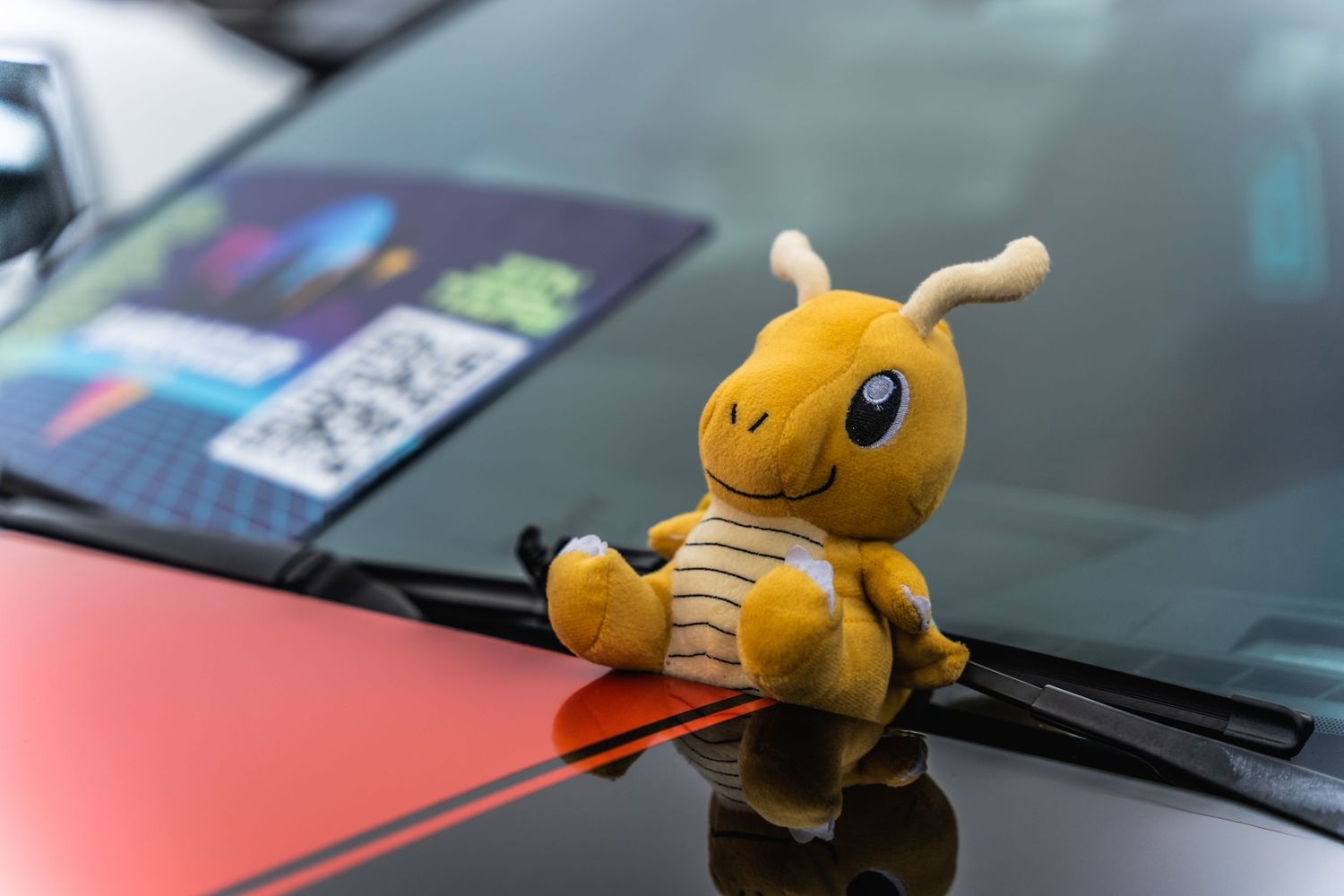 Yellow Dragonite Pokemon plush toy sitting on a car's windshield wiper.
