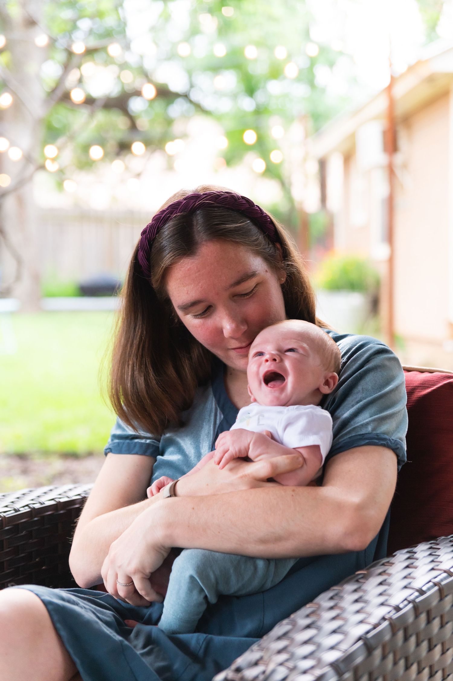 Mother and laughing baby share joyful moment on outdoor patio furniture.