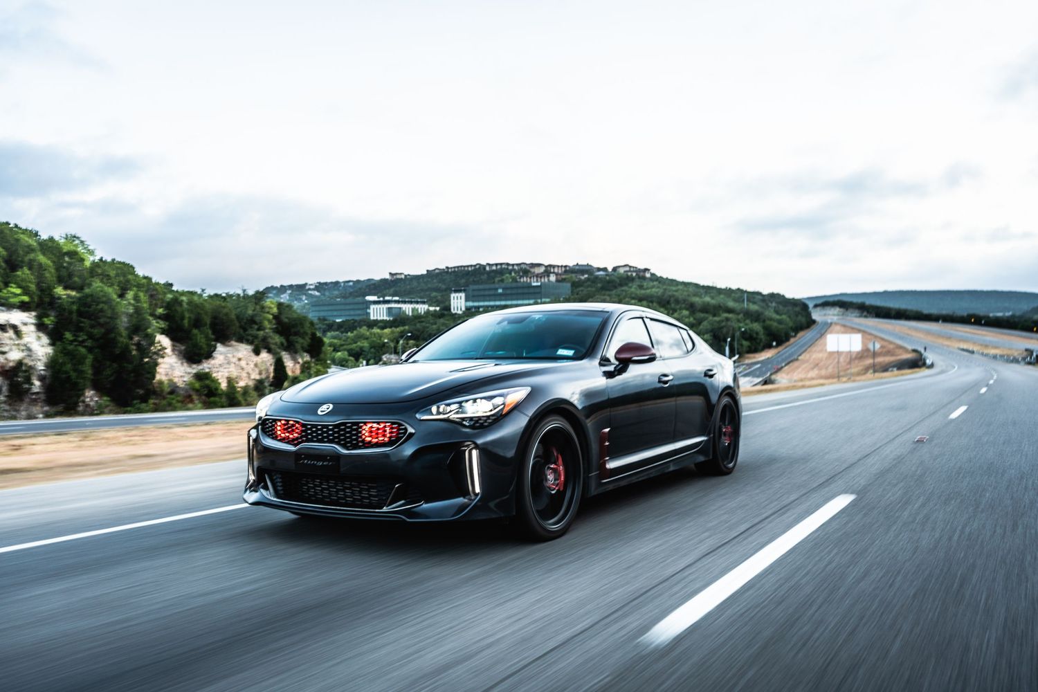 Black Kia Stinger GT captured in motion on a mountain road.