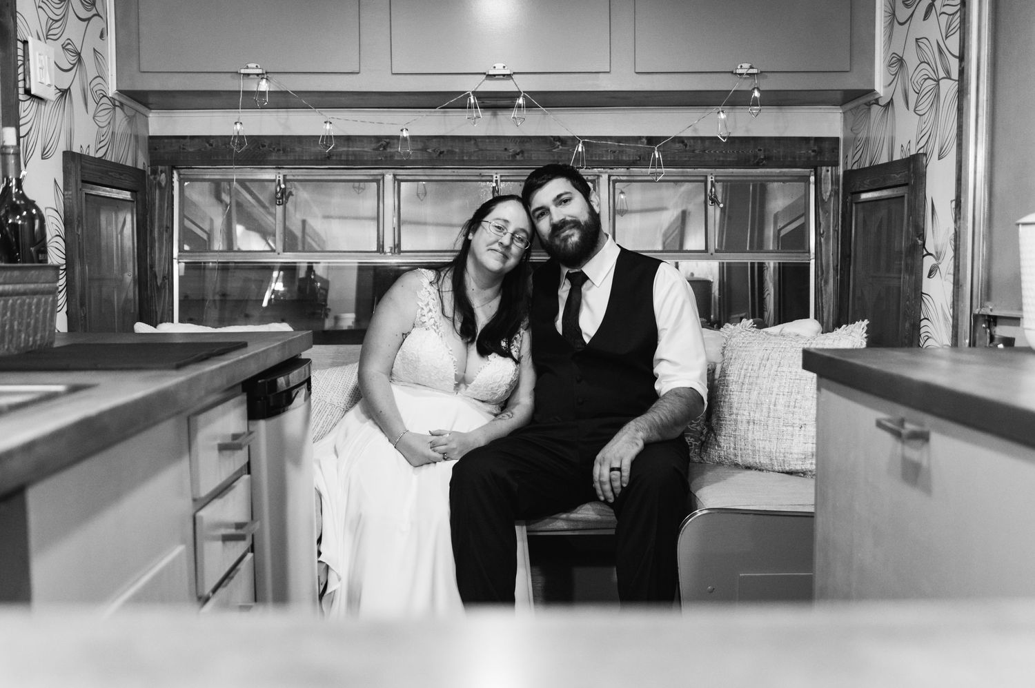 Black and white portrait of newlyweds relaxing in a vintage-style indoor setting.
