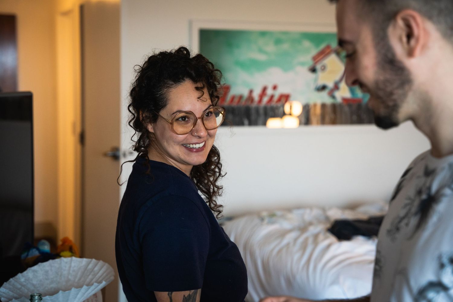 Two people having a casual conversation in an indoor setting with warm lighting and wall art.