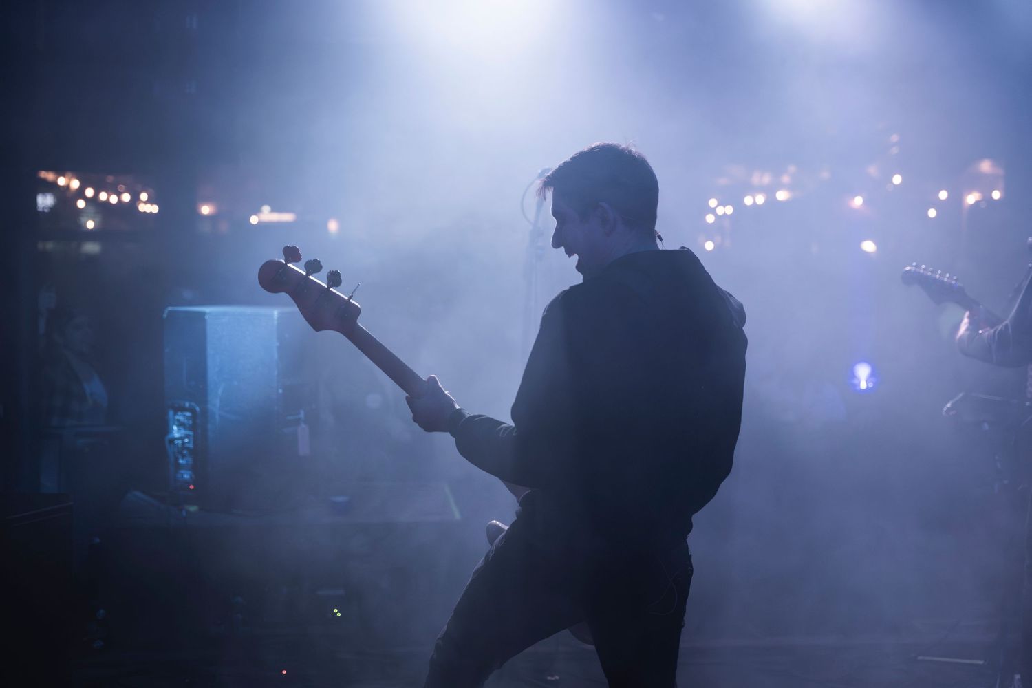 Silhouette of bassist performing against atmospheric fog and stage lights.