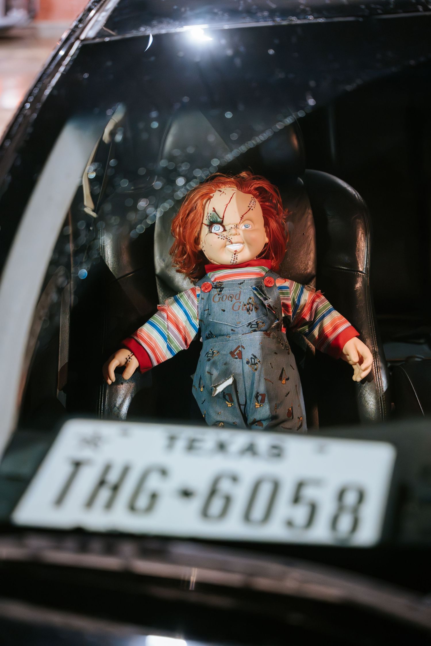 Chucky doll displayed in car with Texas license plate visible.