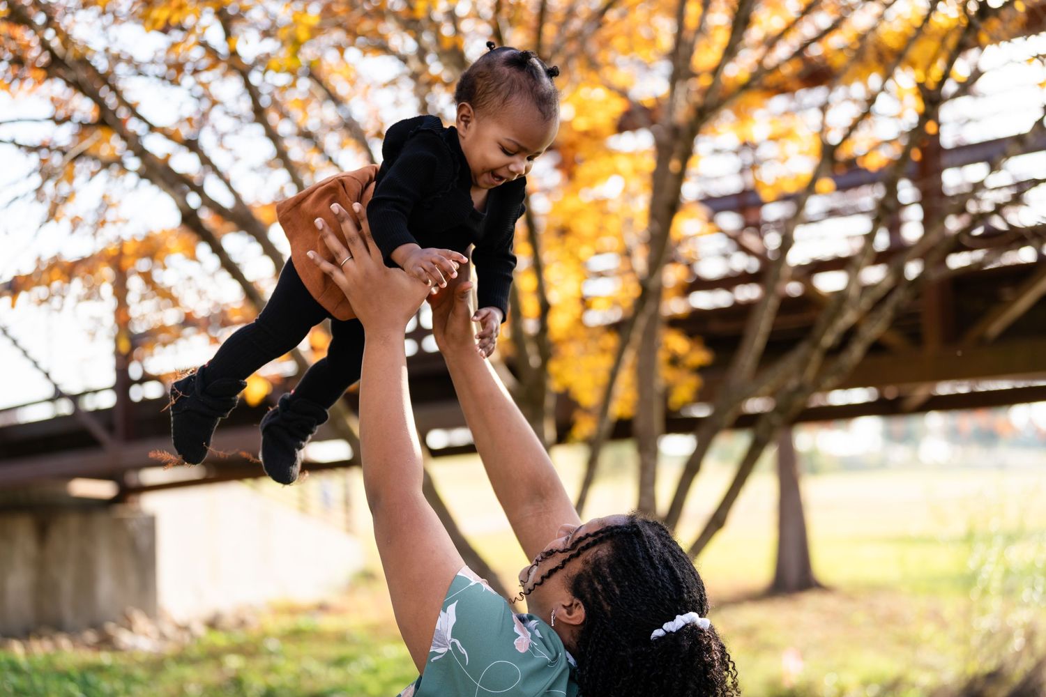 A playful moment captured outdoors with golden autumn foliage in the background.