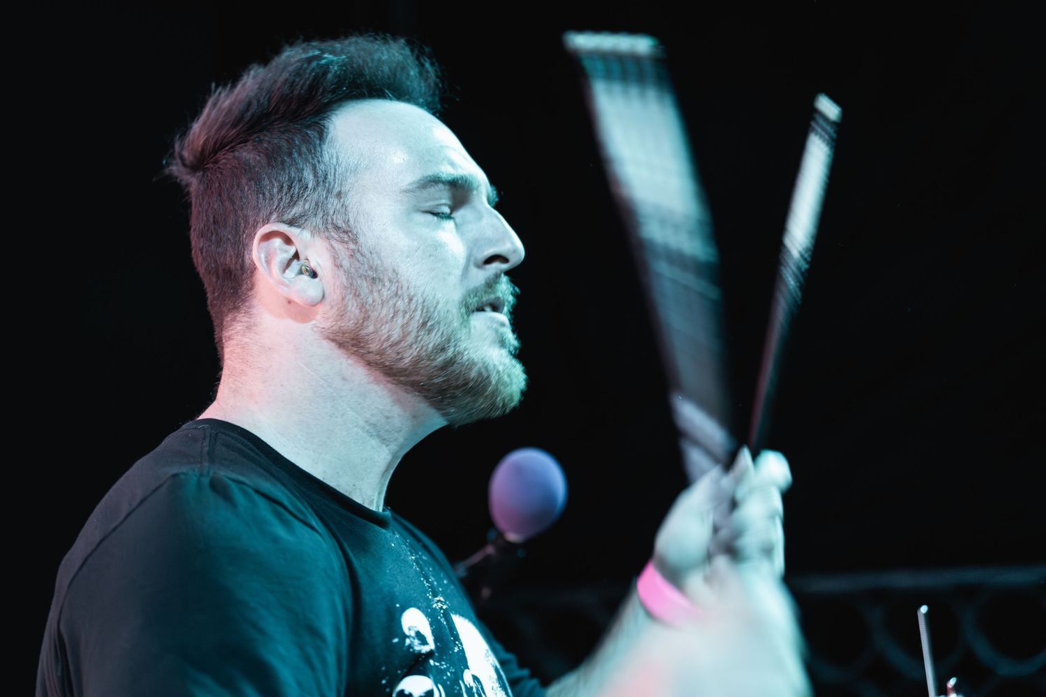 Drummer performs on stage with emotional intensity during live concert performance.