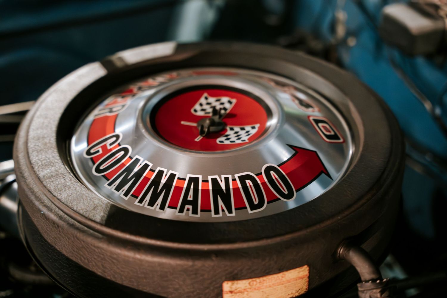 Close up of a red Commando air filter cover on a classic car engine.