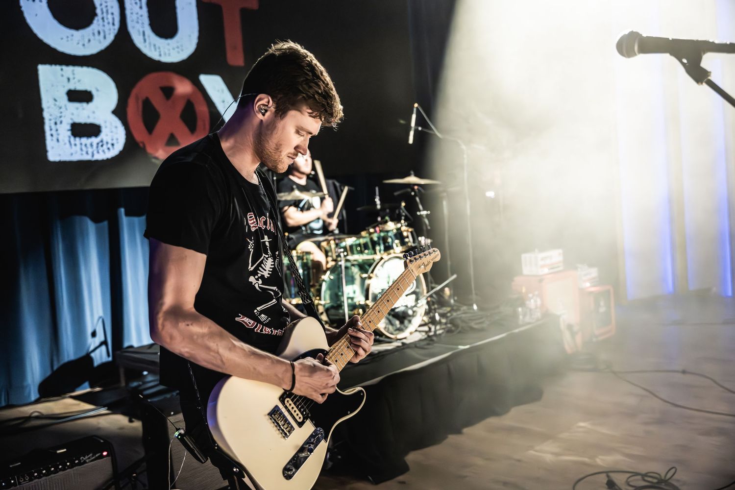 Guitarist performing on stage with guitar under bright lighting at live concert venue.