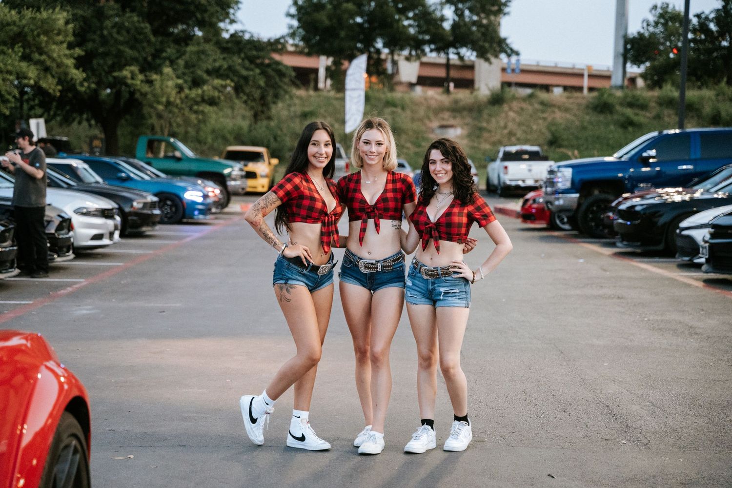 Group posing together at a car enthusiast meetup in matching attire.