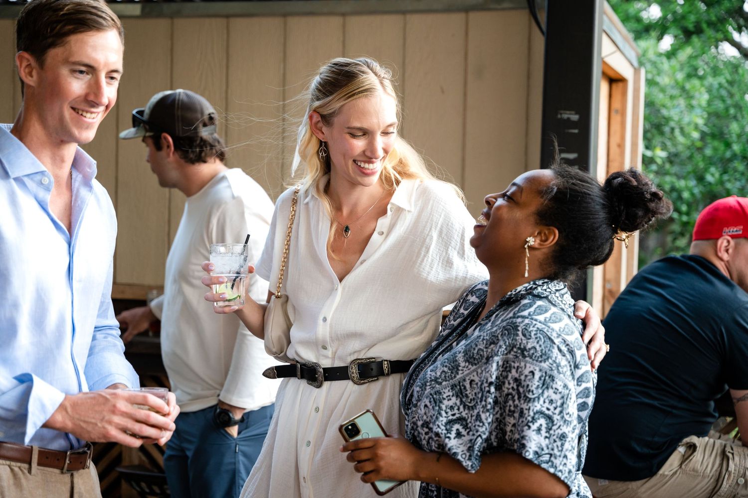 Casual outdoor gathering with people socializing and holding beverages.