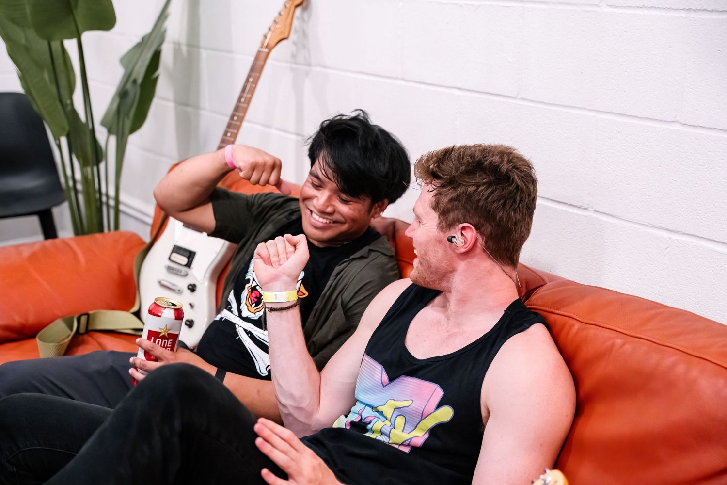 Musicians relaxing on an orange couch during backstage interview or casual conversation.