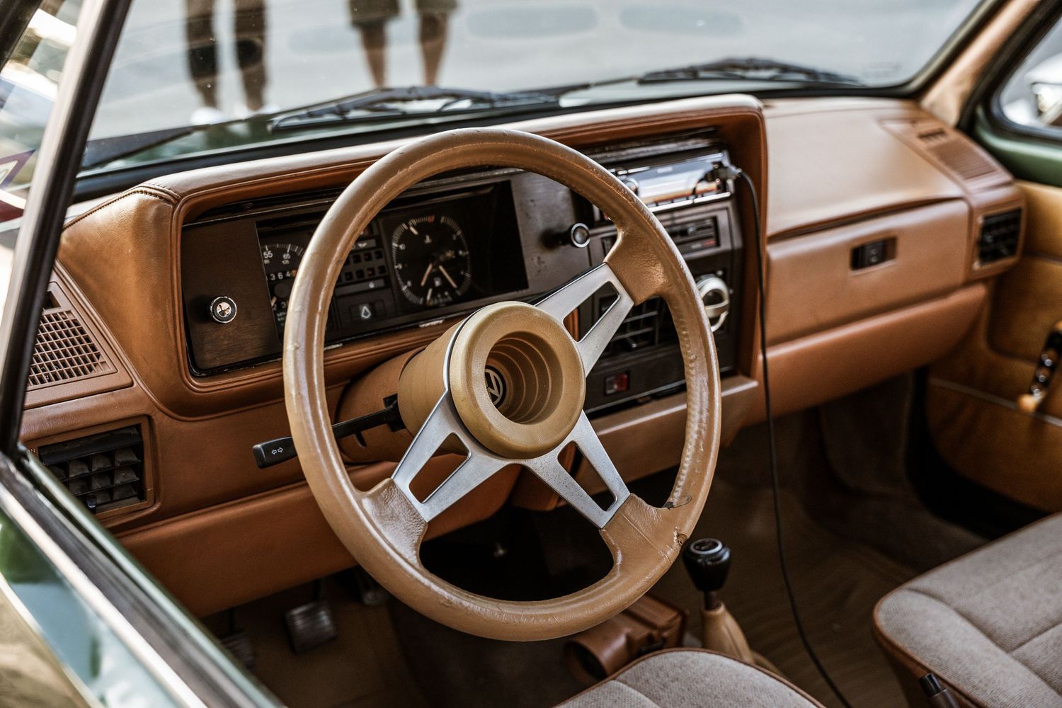 Vintage brown dashboard interior of a classic car with a three-spoke steering wheel.