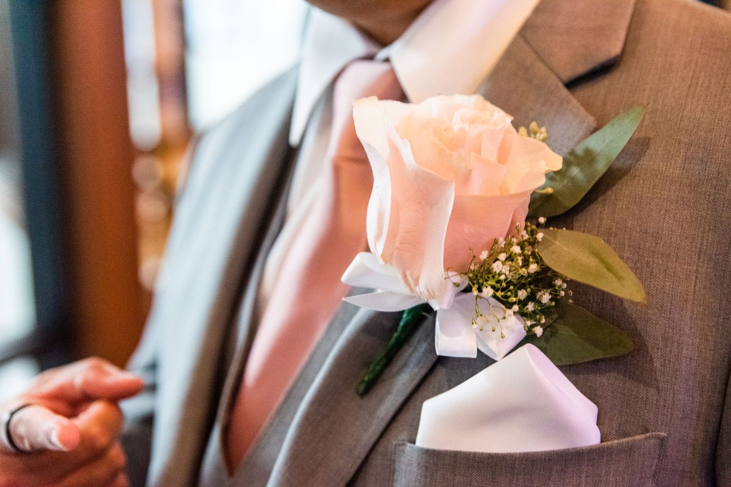 Peach rose boutonniere pinned to brown suit jacket.
