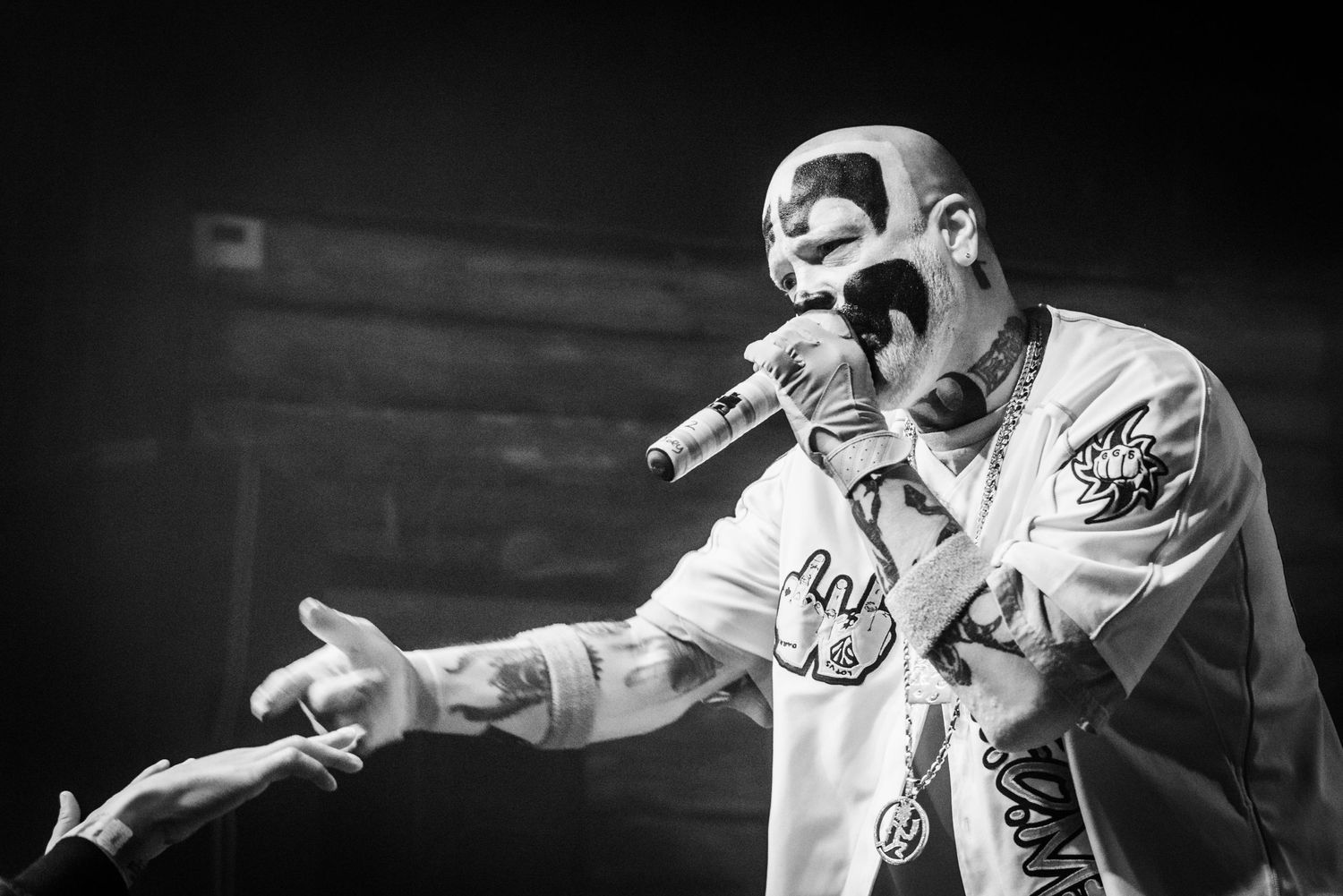 Black and white photo of performer in patterned clothing gesturing during concert.