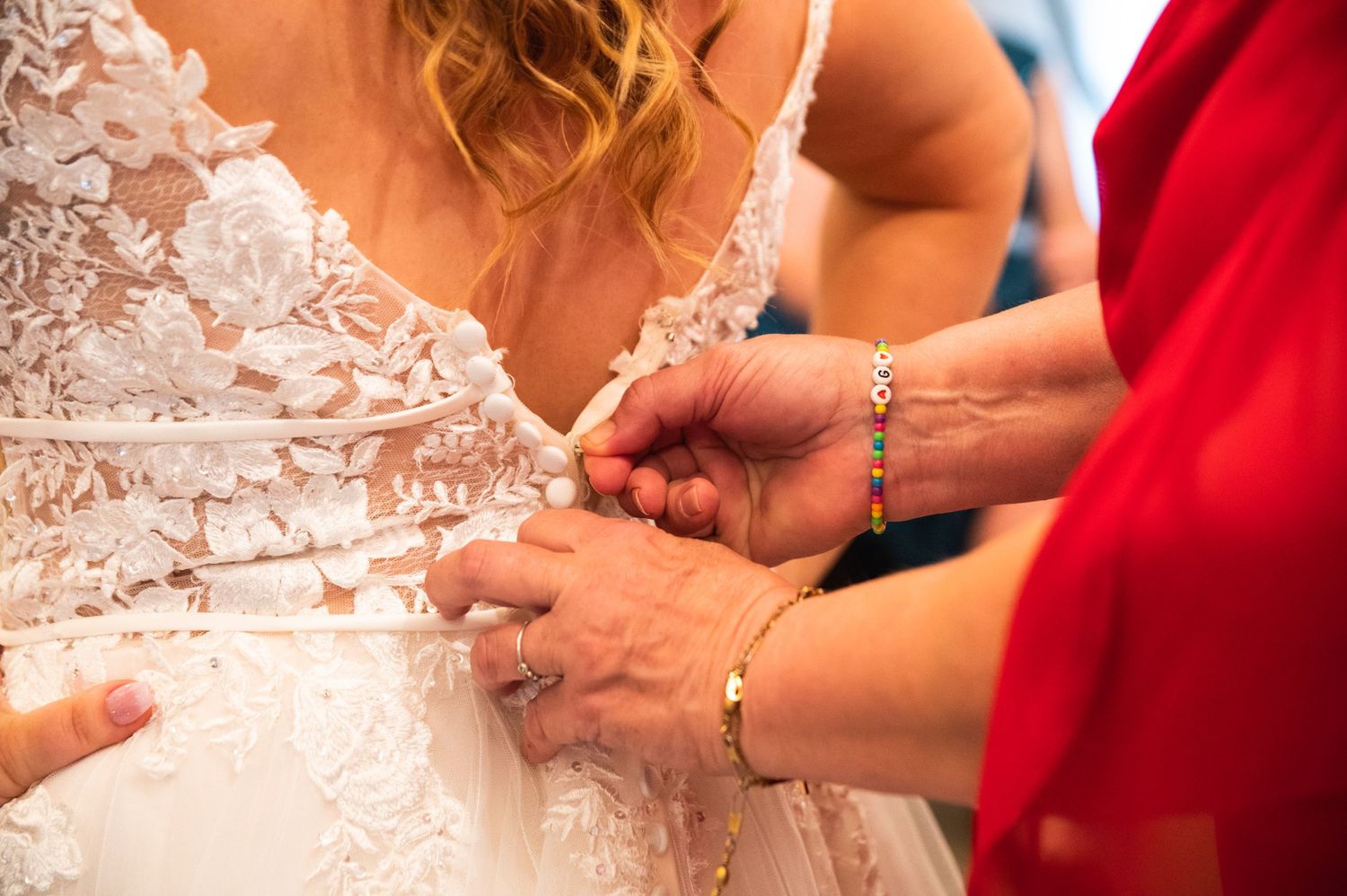Close-up shot of hands adjusting intricate lace details on a wedding dress.