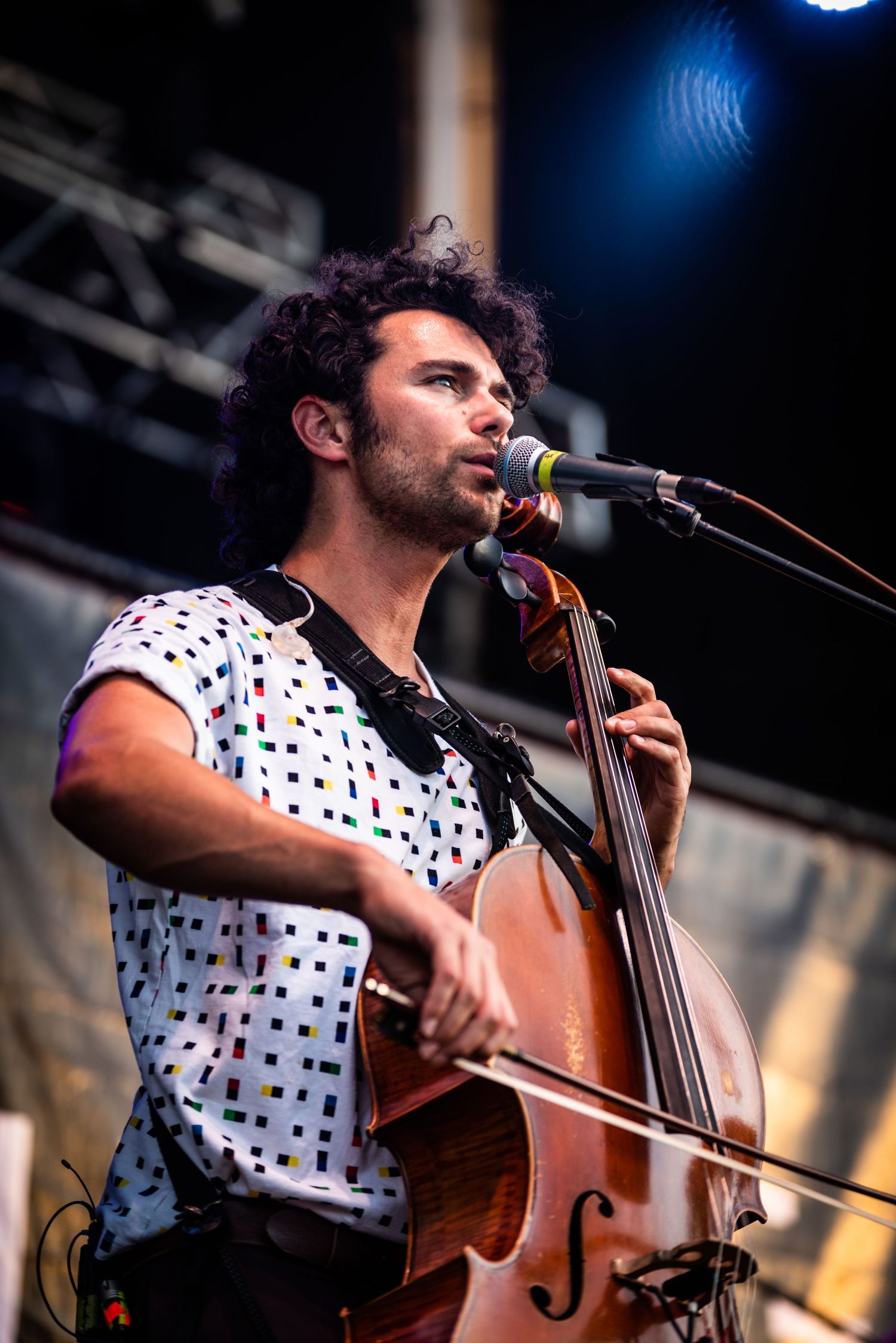 Musician playing upright bass in polka dot shirt during outdoor performance.