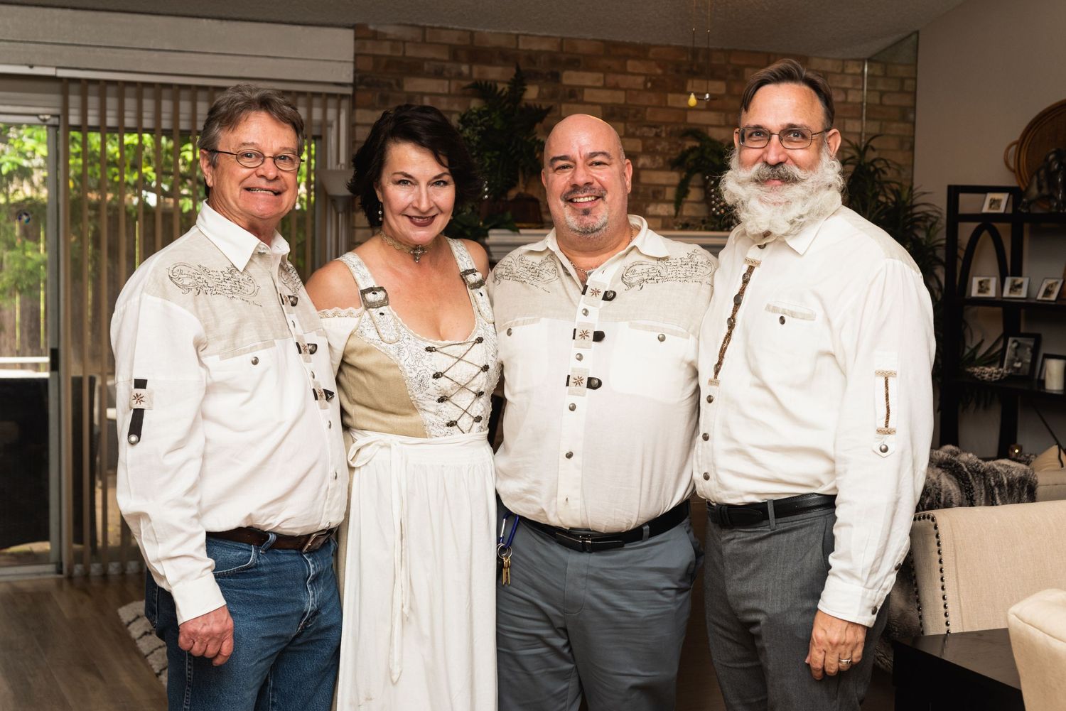 Group photo of four people in matching white shirts at indoor gathering.