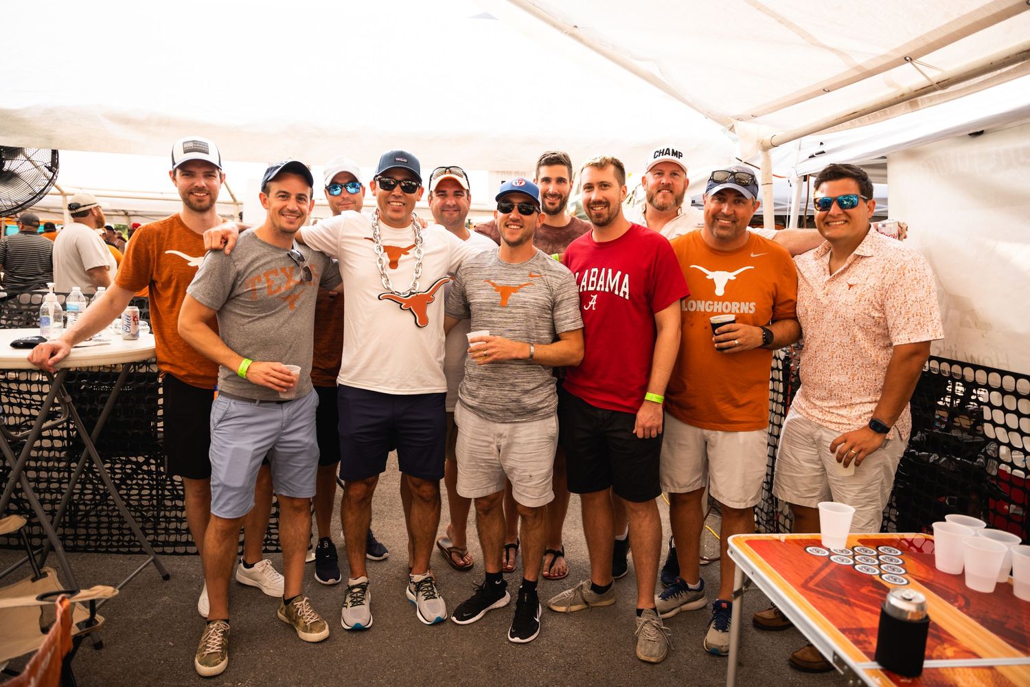 People in casual attire posing together at an outdoor party venue.
