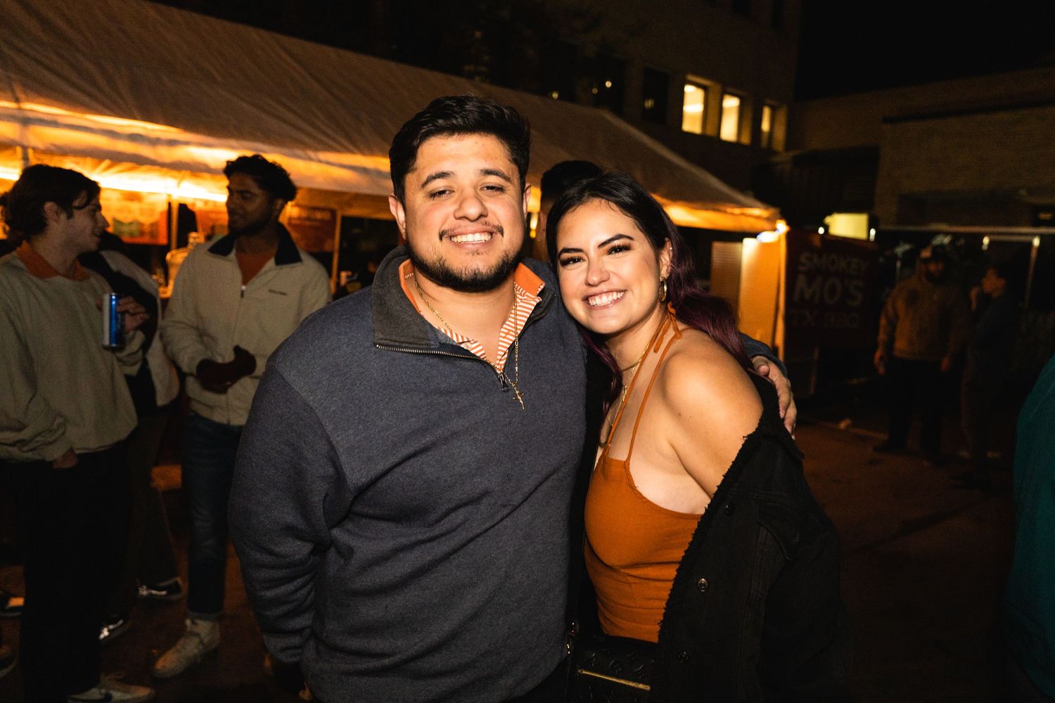 Couple smiling together at an outdoor nighttime event.